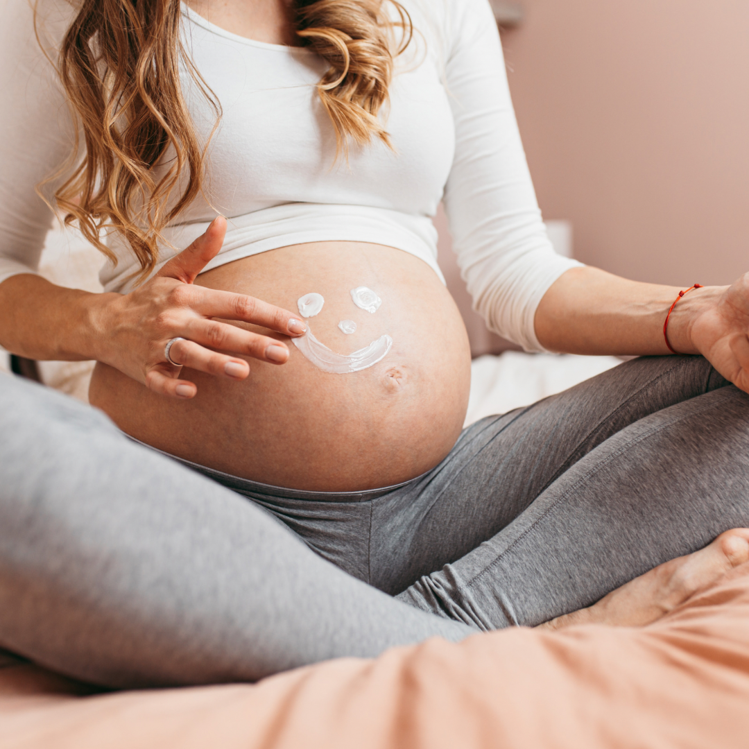 Mulher grávida com as mãos sobre a barriga.