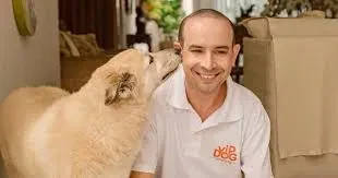 Tio Léo sorrindo enquanto recebe um beijo de um cão