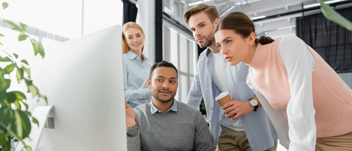 Duas pessoas em um escritório revisando o layout de um site na tela do computador