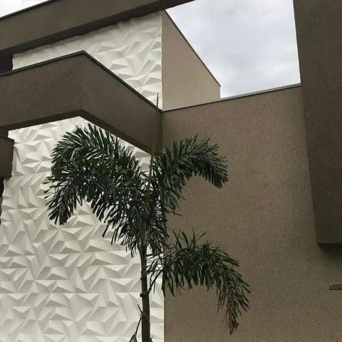 Parede externa com revestimento acrílico de pedras naturais ao lado de painel decorativo