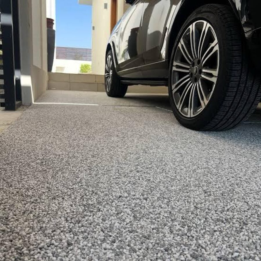 Garagem com piso natural em tom cinza com preto e carro estacionado