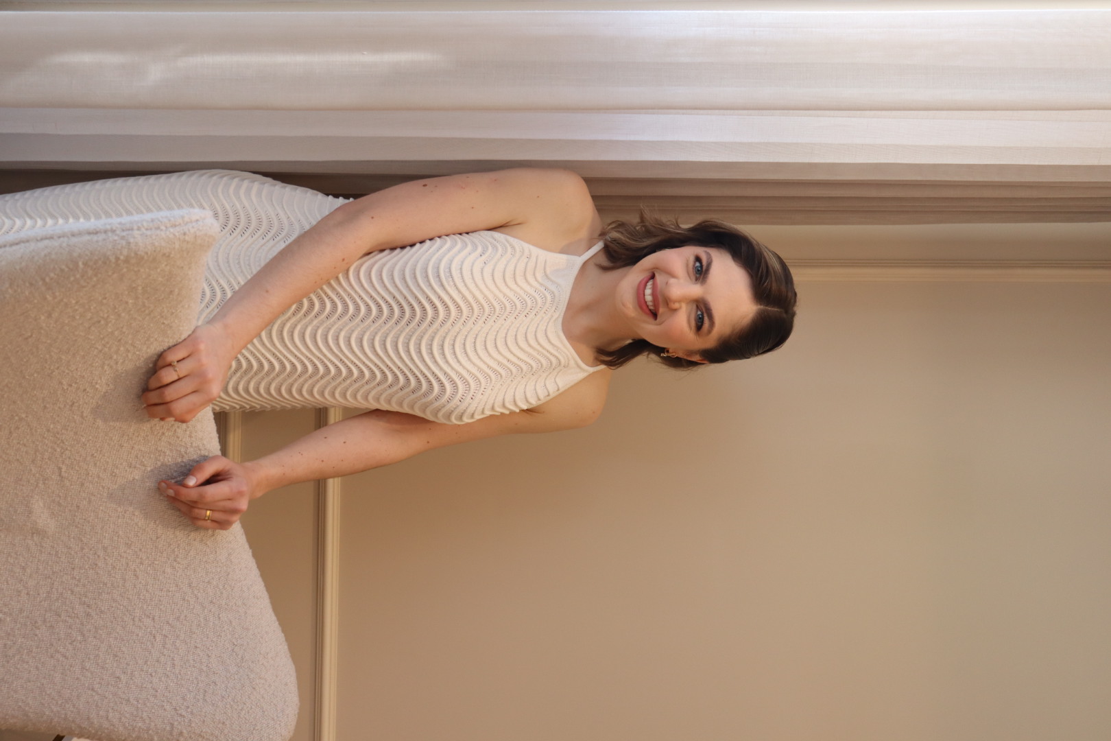 Karine Gräbin sorrindo, com as mãos apoiadas na poltrona