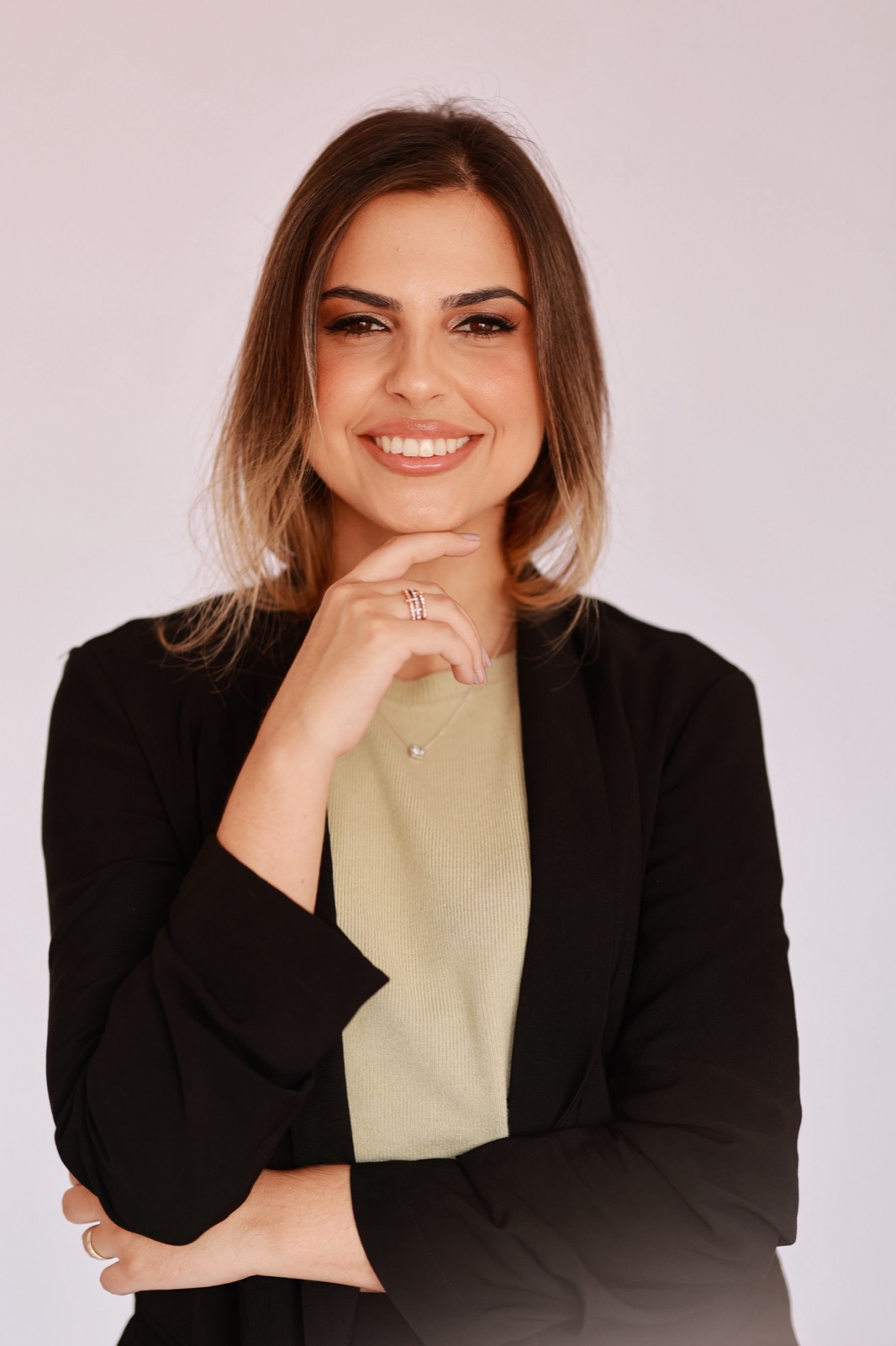 Joanna Carollo de blazer preto, com a mão junto ao rosto