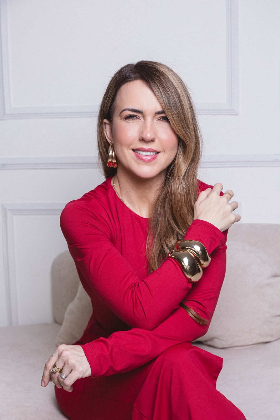 Carolina Tavares sorrindo, sentada em um sofá