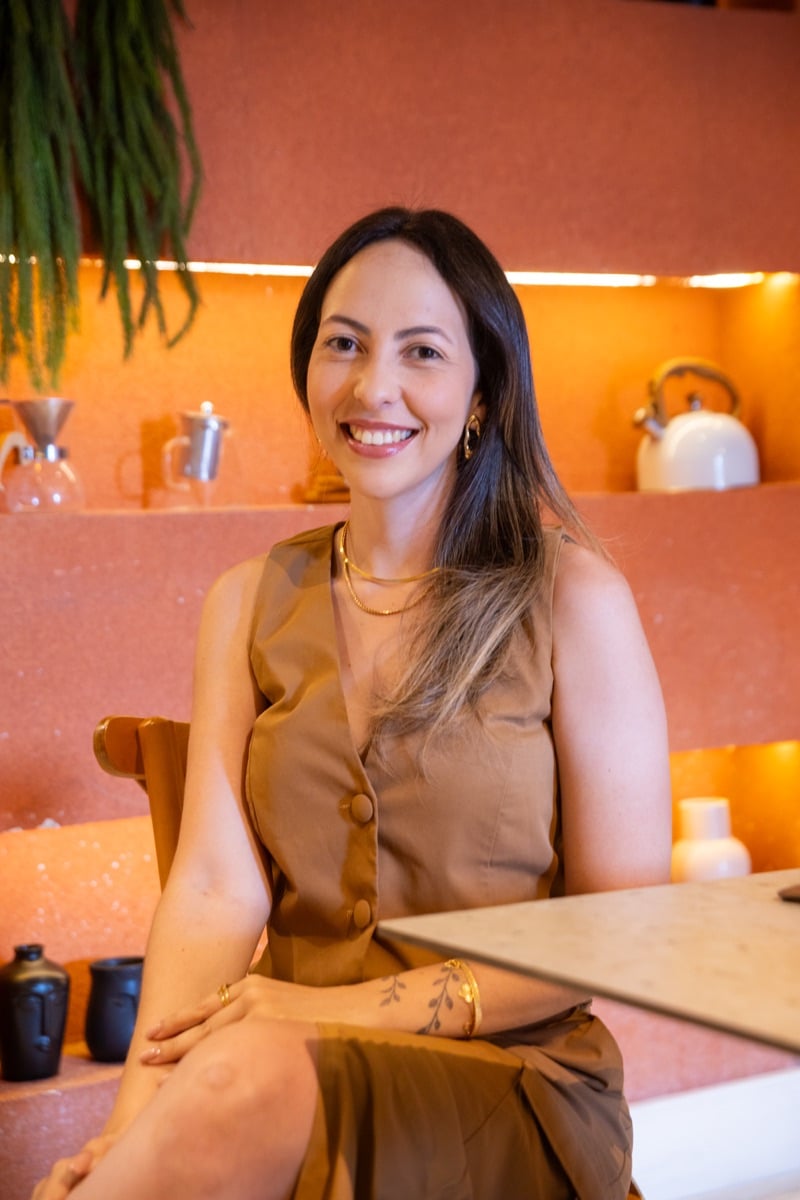 Thalia Cardoso sentada em um ambiente acolhedor.