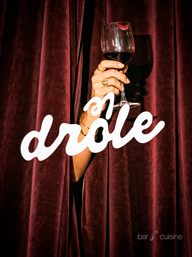 Drôle — mão com taça entre cortinas de veludo