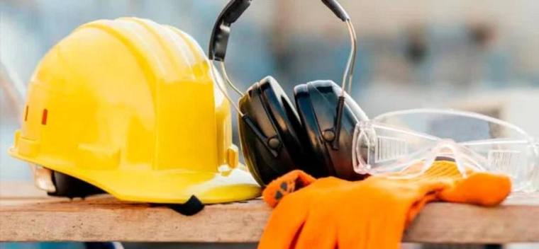Capacete, protetor auricular, óculos de proteção e luvas sobre uma bancada