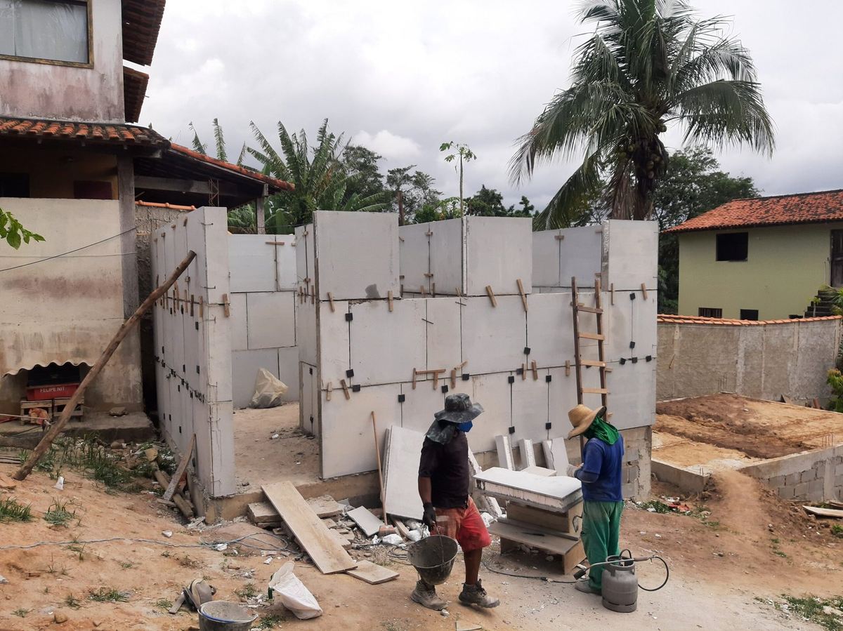 Operários trabalhando em construção residencial com paredes pré-moldadas