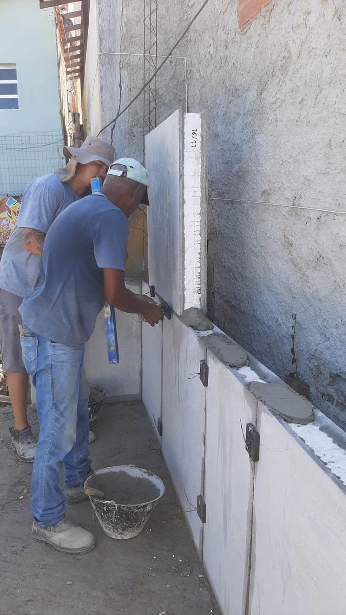 Trabalhadores montando paredes pré-moldadas em uma casa