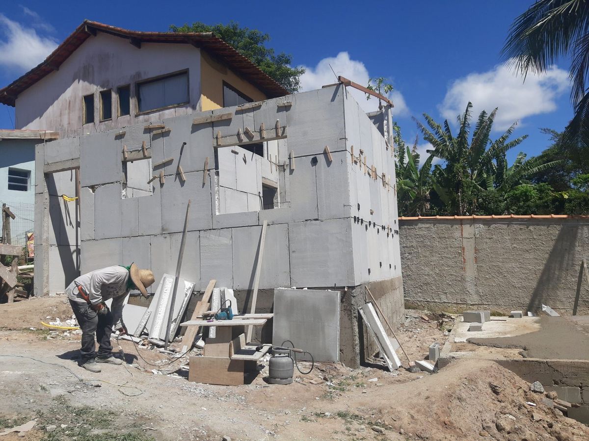 Trabalhador montando paredes de uma casa pré-moldada