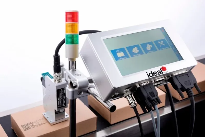Codificadora Ideal marcando data de fabricação, validade e QR code em caixas na esteira