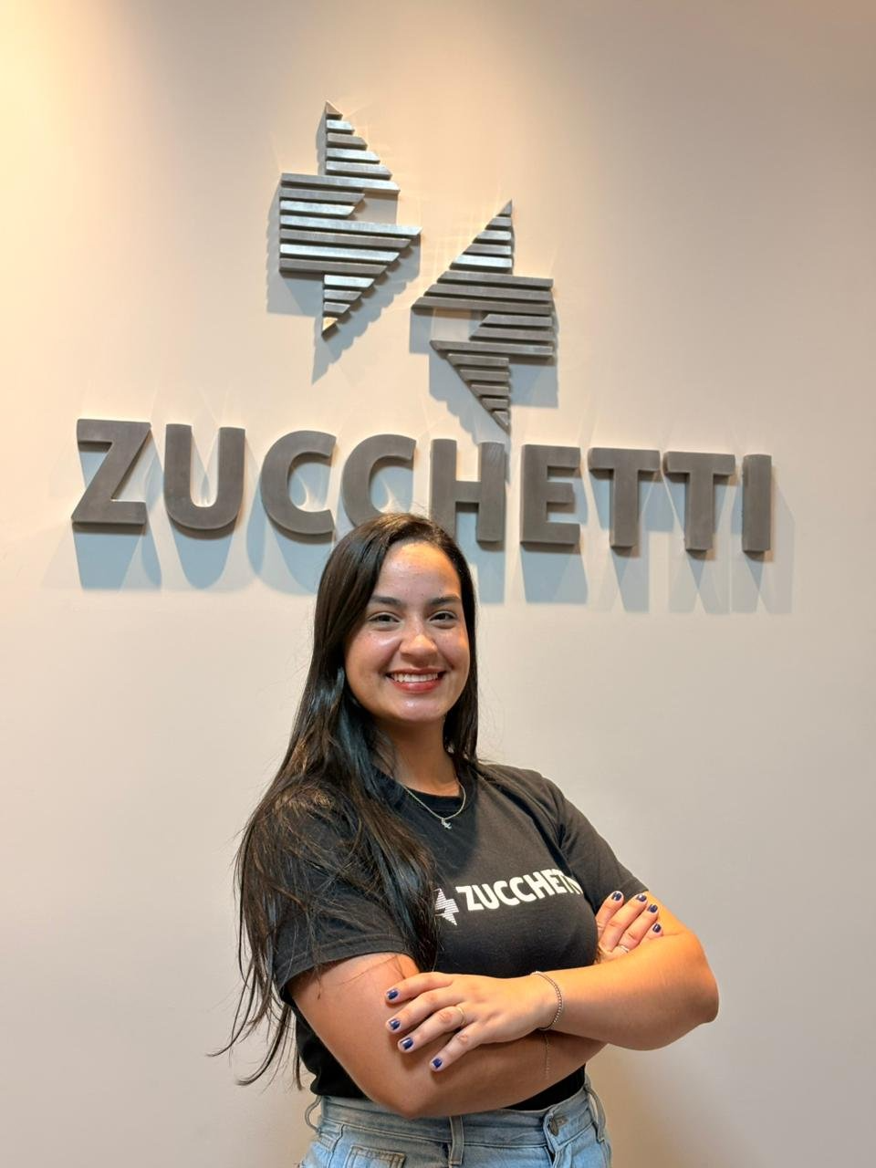 Amanda Silva, de Gestão de Talentos, em frente ao logo da Zucchetti