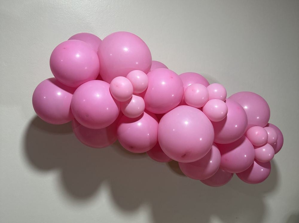 Guirlanda de balões rosa presa na parede, feita pela Brenda
