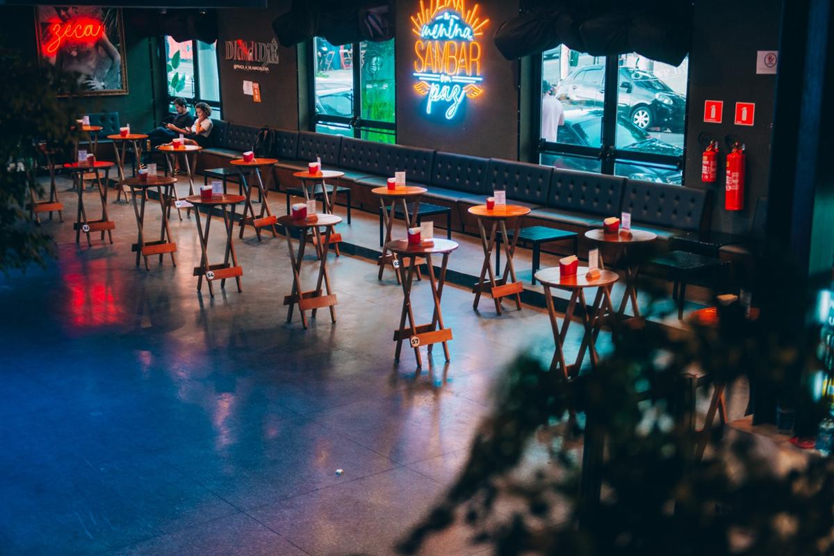 Pista com mesas altas e letreiros de neon