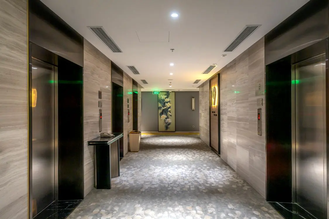 Hall contemporâneo com quatro elevadores de aço e painéis de chamada, sem pessoas