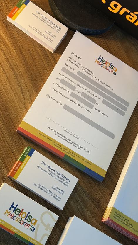 Bloco de atestado e cartões de visita de uma clínica odontológica